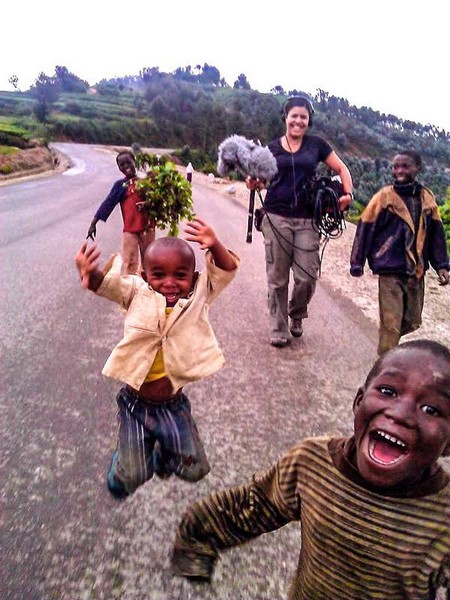 Ana walks along a road in Rwanda with four excited young boys