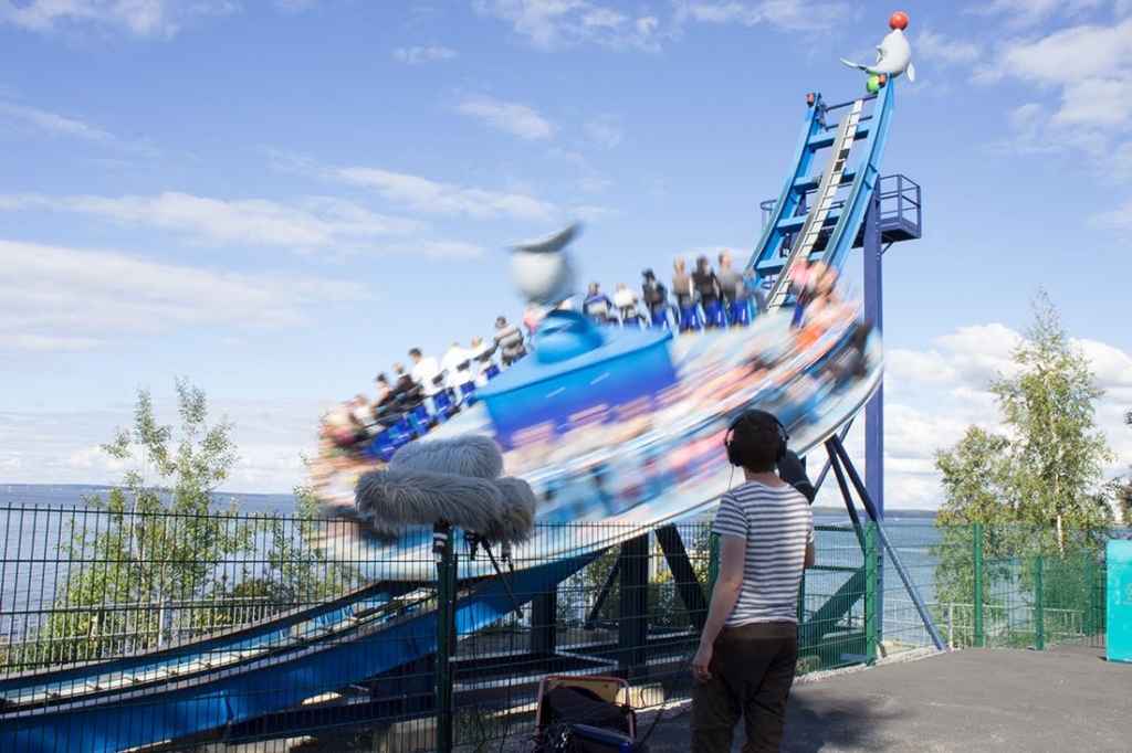 A boom mic faces a fast spinning ride full of people