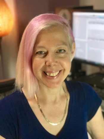 Becky Allen has pink and blonde hair and sits in front of her workstation