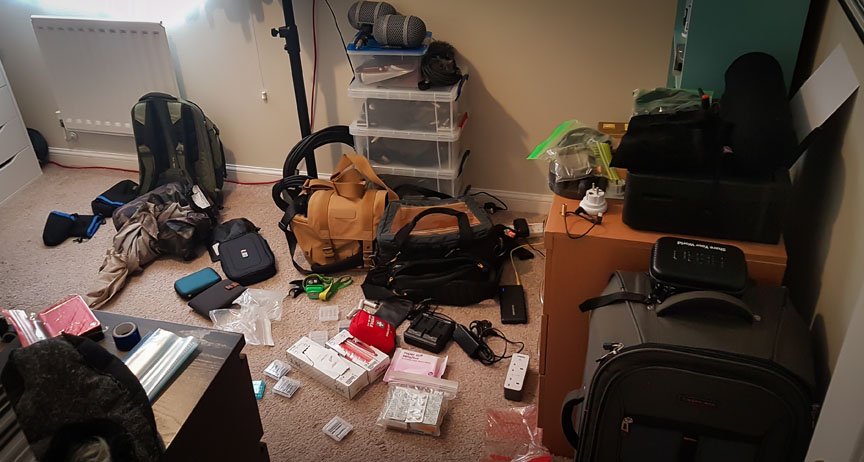 Backpacks, recordings gear, and clothing lay on the floor.