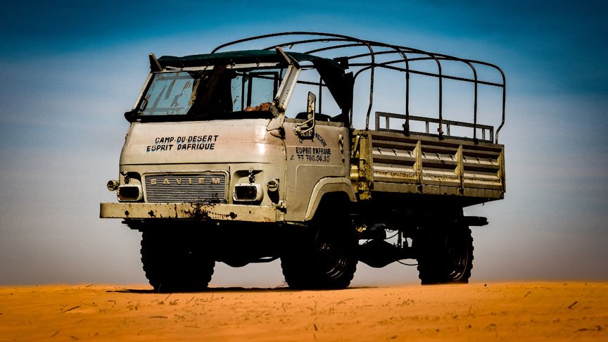 A large military truck has a bed for transporting travelers.