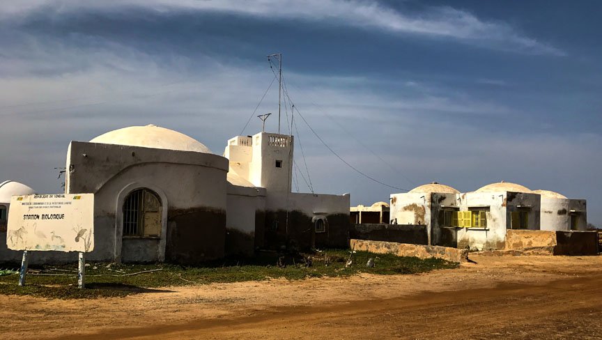 White buildings with round roofs sit in the desert.