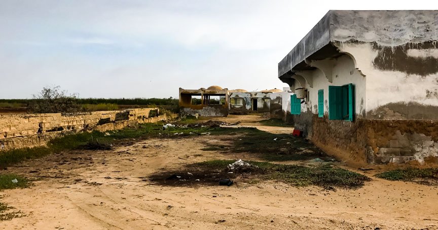 Behind the buildings there is a fence and flat fields.