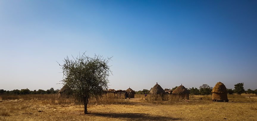 Six small huts outline the horizon.