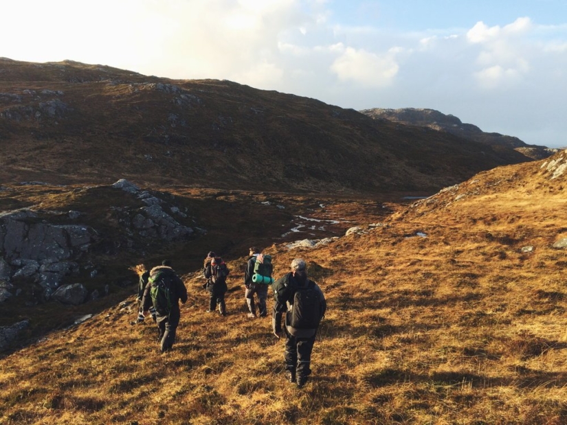 A group of people hike through the Scottish hills.