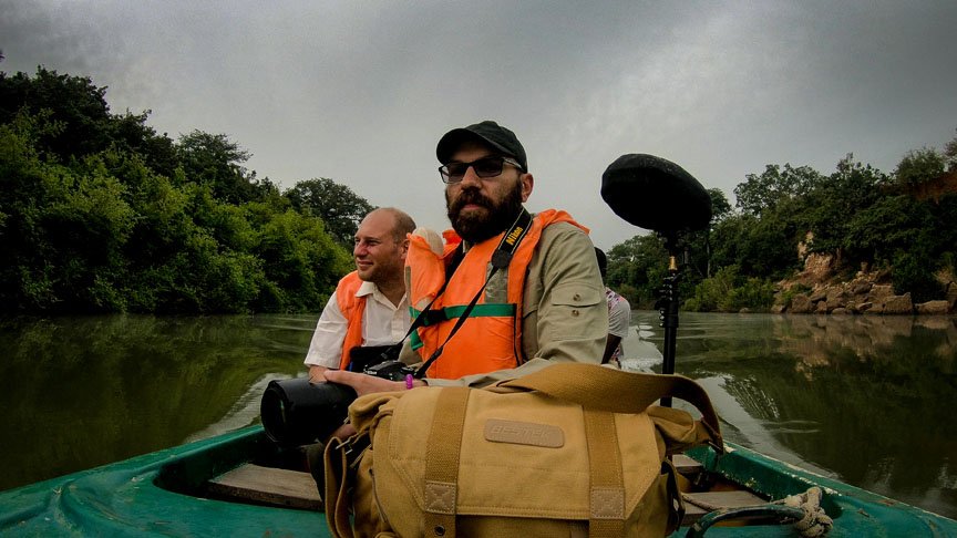 Three men observe the natural setting from a drifting canoe.