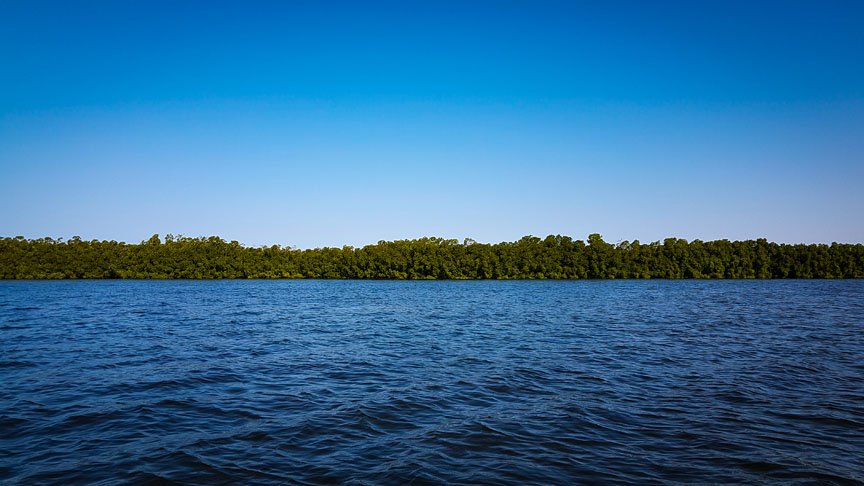 The dark blue water is lined by dark green trees and brush.