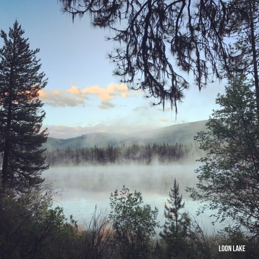 Fog drifts above a calm lake.