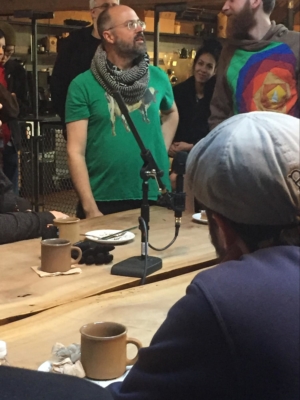 Damian and Anton stand in a crowded coffee shop hosting their podcast.