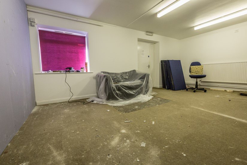 An empty construction area with only a plastic-covered couch