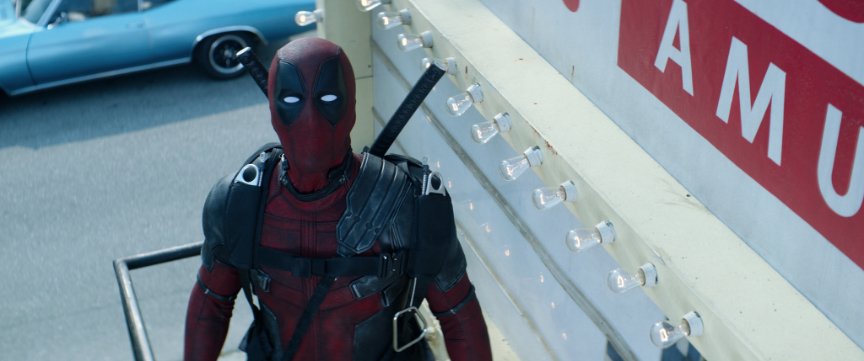 Deadpool looks up as he stands on a billboard platform.