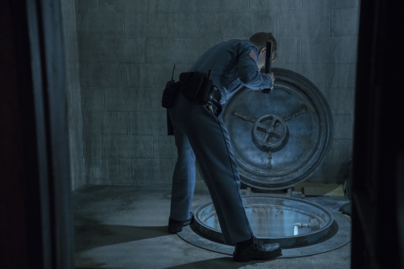 A prison guard looks into a manhole inside the prison.