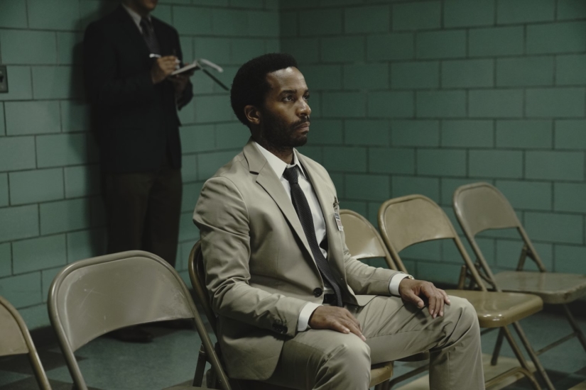 Henry Deaver (Andre Holland) sits in a suit in a prison holding area.
