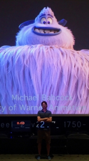 A man stands in front of a screen with the yeti standing tall