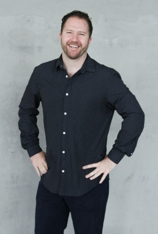 A man smiles with his hands on his hips