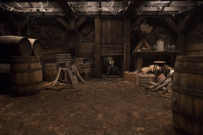 A small boy shines his light up a dumbwaiter from the wine cellar.