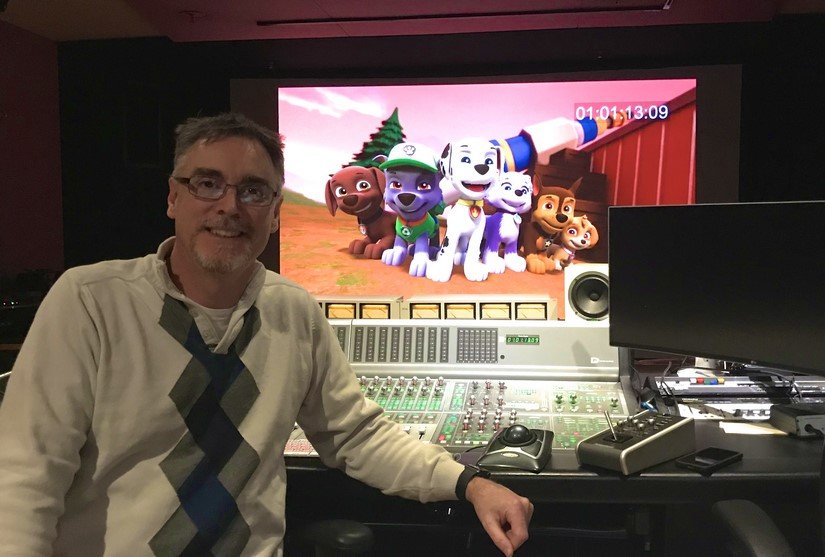 A man stands in front of his soundboard with PAW Patrol on the screen.