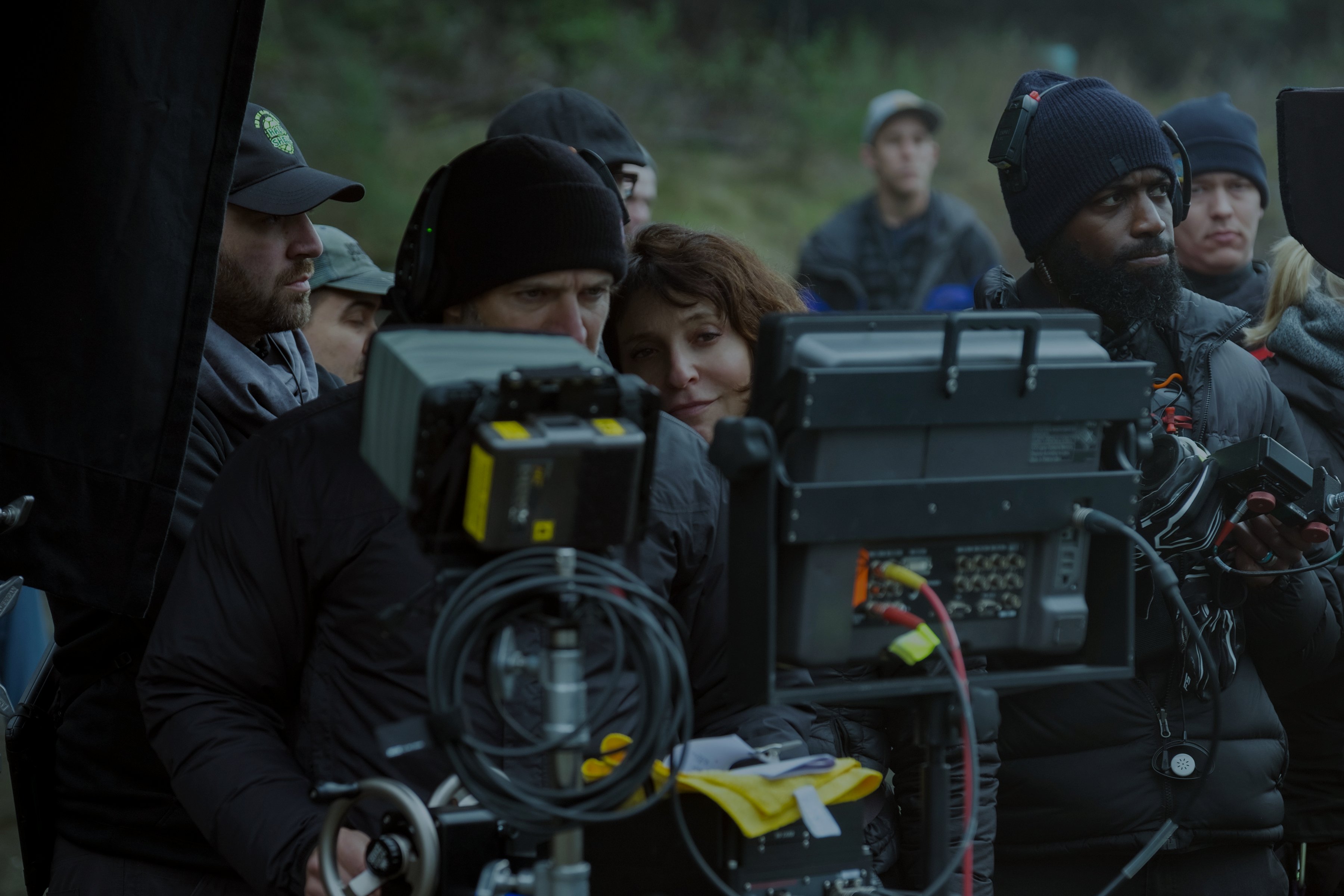 The film crew looks at the footage on camera screen.