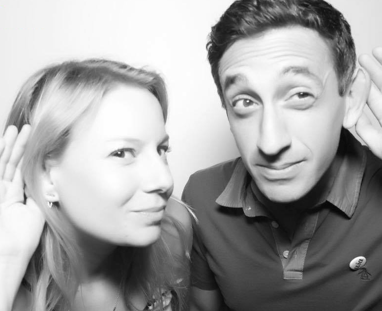 A woman and man put their hands to their ears to listen closely.