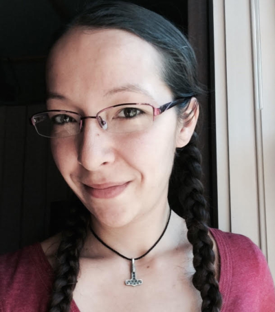A woman with brown braids and glasses smiles.