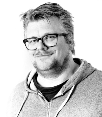 A man with a blonde beard and glasses smiles.