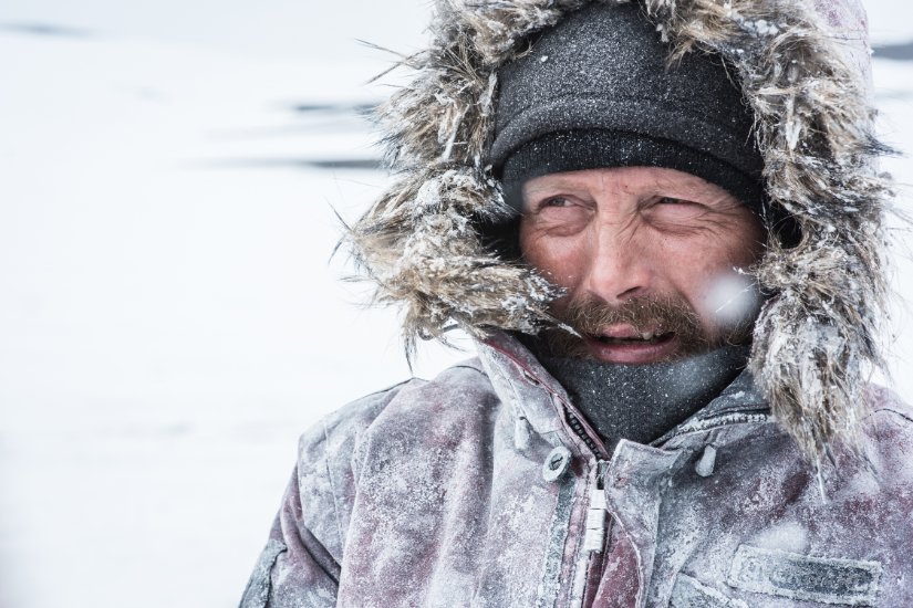 A man squints as his clothing is plastered in arctic snow.