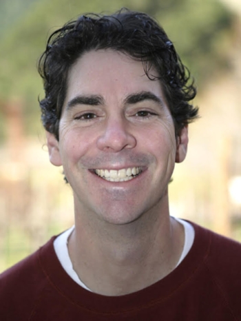 A man with dark hair smiles.
