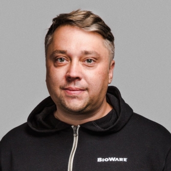 A man in a hoodie smiles gently.