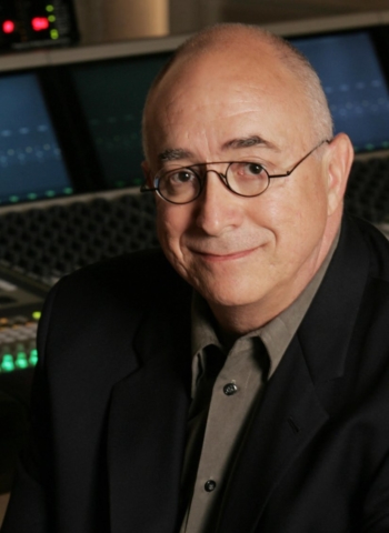 An older man with glasses looks up and smiles.