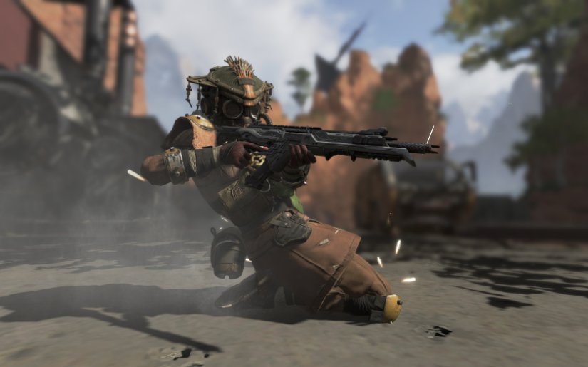 A soldier slides across the ground shooting his rifle.