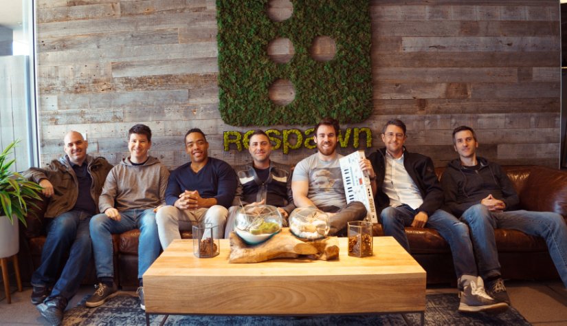 Seven men sit together on a couch.