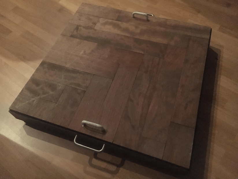 A shallow wooden box with a cover with handles