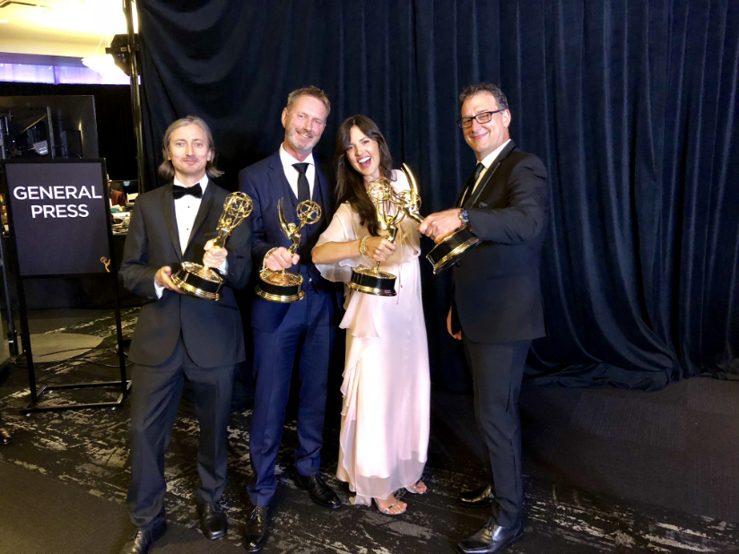 Four fashionable dressed people hold Emmy awards