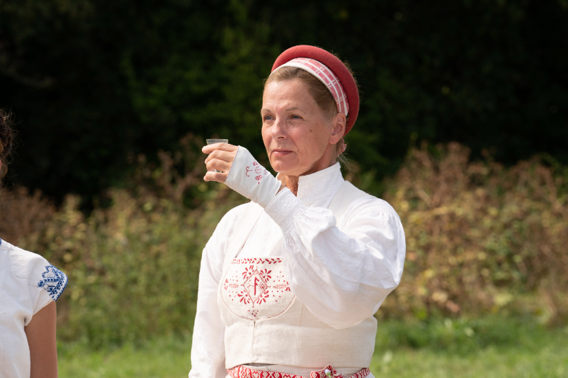 A woman in Swedish garb presents a toast.